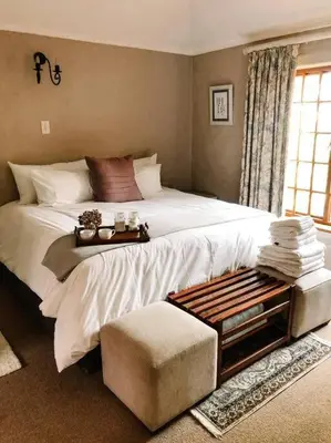a bedroom with a large white bed with a ottoman at Eden Rain in Dullstroom