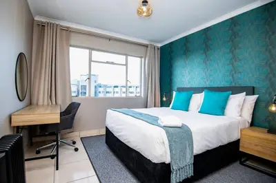 a bedroom with a bed and a desk and a window at Unit 416 at Menlyn Place in Pretoria
