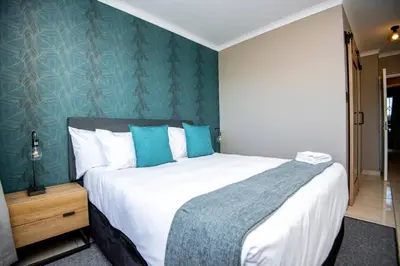 a bedroom with a large bed with blue walls at Unit 416 at Menlyn Place in Pretoria