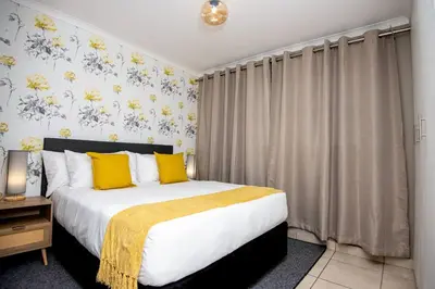 a bedroom with a large bed with yellow pillows at Unit 416 at Menlyn Place in Pretoria