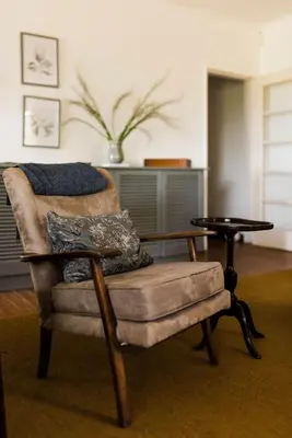 a living room with a chair and a table at Verkijken Cottage in Haenertsburg