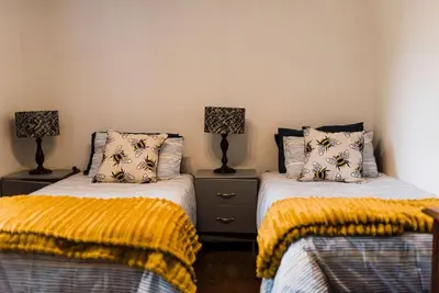 a bedroom with two beds with yellow blankets at Verkijken Cottage in Haenertsburg
