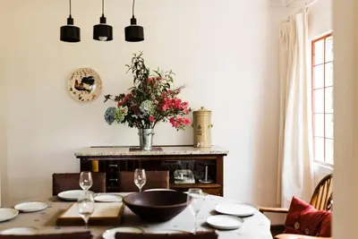 a dining room with a table with a vase of flowers at Verkijken Cottage in Haenertsburg