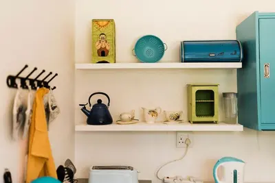 a kitchen with shelves on the wall with a sink at Verkijken Cottage in Haenertsburg