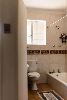 a bathroom with a toilet and a tub and a window at Verkijken Cottage in Haenertsburg