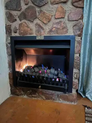 a stone fireplace with a fire in it at Hakuna Matata-Bela Bela in Moheme