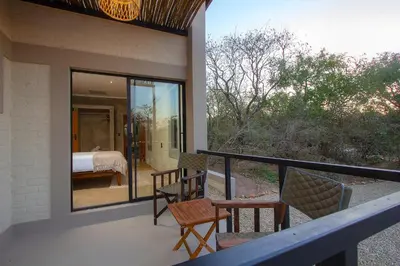a balcony of a house with a bed and chairs at MRLTH Luxury Safari Villa, Close to KNP, Giraffe-Feeding-Tower, Spa-Bath, Boma in Marloth Park