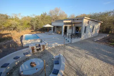 a small house with a swimming pool in front of it at MRLTH Luxury Safari Villa, Close to KNP, Giraffe-Feeding-Tower, Spa-Bath, Boma in Marloth Park