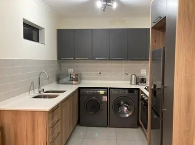 a kitchen with a washer and dryer and a sink at Luxury 1bed Serengeti OliveWood ORT Airport in Kempton Park