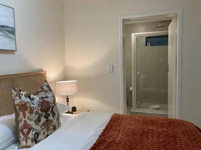 a bedroom with a bed and a window with a shower at Luxury 1bed Serengeti OliveWood ORT Airport in Kempton Park