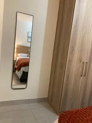 a bedroom with a mirror and a wooden cabinet at Luxury 1bed Serengeti OliveWood ORT Airport in Kempton Park