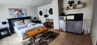 a bedroom with a bed and a table and a kitchen at Mountain Vue in Hartbeespoort