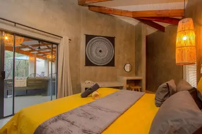 a bedroom with a large bed with a yellow blanket at Ibhubesi house in Marloth Park