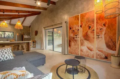 a living room with lions painted on the wall at Ibhubesi house in Marloth Park