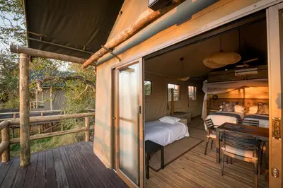 a room with a bed and a desk on a deck at Nkuhlu Tented Camp in Skukuza