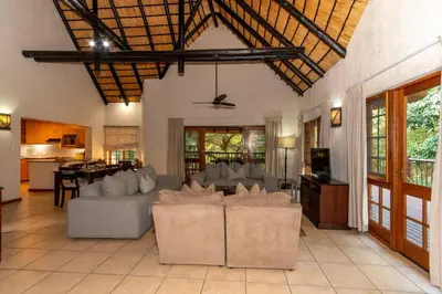 a living room with white couches and a kitchen at Kruger Park Lodge Unit No. 254 in Hazyview