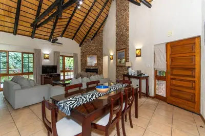 a living room with a wooden table and chairs at Kruger Park Lodge Unit No. 254 in Hazyview