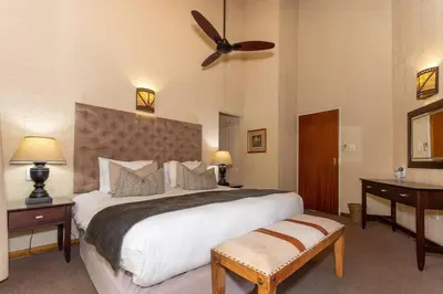 a bedroom with a large bed with a ceiling fan at Kruger Park Lodge Unit No. 254 in Hazyview