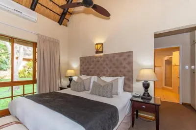 a bedroom with a large bed and a ceiling fan at Kruger Park Lodge Unit No. 254 in Hazyview