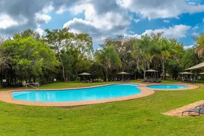 a swimming pool in a park with grass and trees at Kruger Park Lodge Unit No. 254 in Hazyview