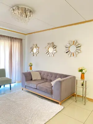 a living room with a couch and two mirrors at Siena Sun Apartment 6 with water reserve in Midrand