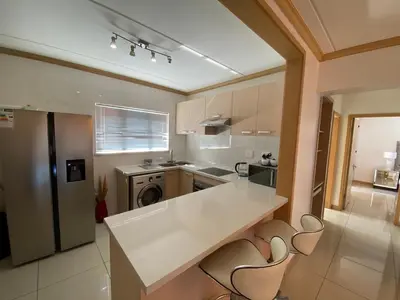 a kitchen with a white counter and chairs in it at Siena Sun Apartment 6 with water reserve in Midrand