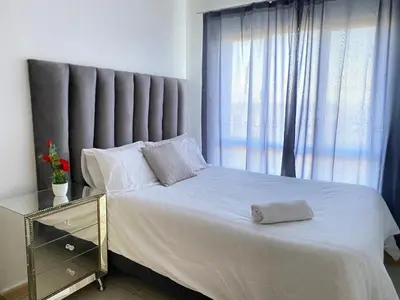 a bedroom with a white bed with a large window at Siena Sun Apartment 6 with water reserve in Midrand