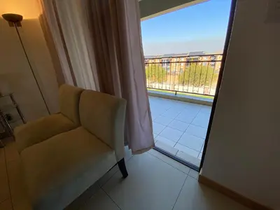 a chair in a room with a view of a balcony at Siena Sun Apartment 6 with water reserve in Midrand