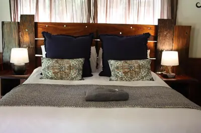 a bed with blue pillows and a wooden headboard at House On Blyde in Kampersrus AH