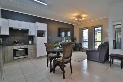 a kitchen and living room with a table and chairs at Luxury Lowveld Apartment in Nelspruit