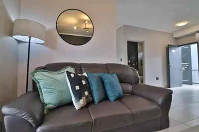 a brown leather couch with pillows in a living room at Luxury Lowveld Apartment in Nelspruit