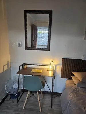 a desk in a bedroom with a bed and a mirror at Sable Sunset Guesthouse in Trichardt