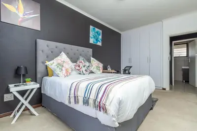 a bedroom with a large bed with a gray wall at The Sunrise in Midrand