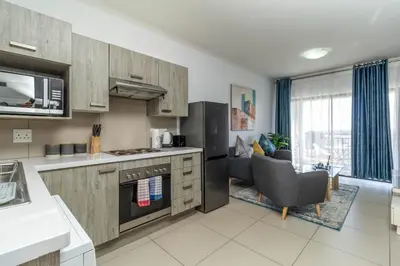 a kitchen with wooden cabinets and a living room at The Sunrise in Midrand
