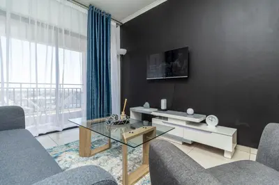 a living room with a glass table and a large window at The Sunrise in Midrand