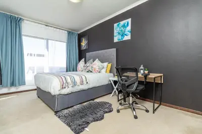 a bedroom with a bed and a desk and a chair at The Sunrise in Midrand