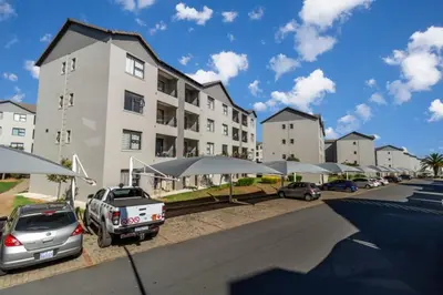 a parking lot with cars parked in front of a building at The Grandeur- with back up power in Midrand
