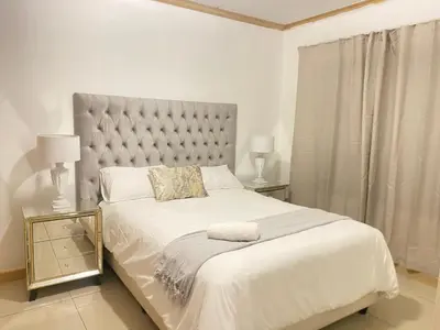 a white bedroom with a large bed and two lamps at Siena Sun Guesthouse Rooms and Breakfast Option in Midrand