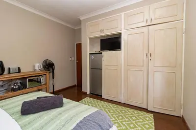 a bedroom with white cabinets and a bed with a television at Somethin Special in Mokopane