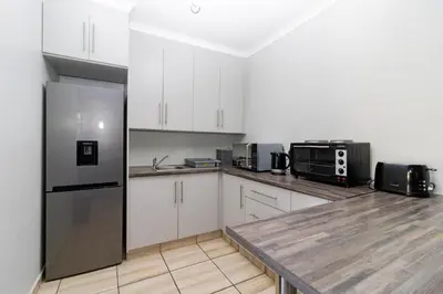 a kitchen with white cabinets and a stainless steel refrigerator at Somethin Special in Mokopane
