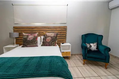 a bedroom with a bed and a blue chair at Somethin Special in Mokopane