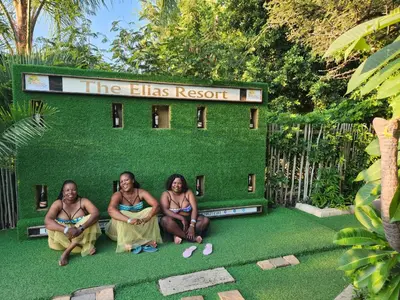 a group of three women sitting in front of a green establishment at The Elias Resort in Septimus