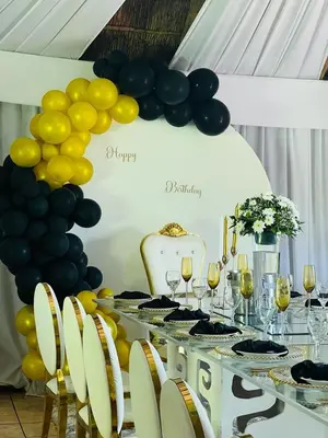 a table with black and yellow balloons and wine glasses at The Elias Resort in Septimus