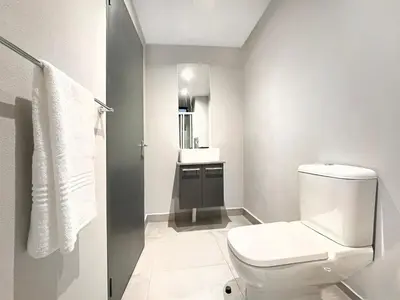 a white bathroom with a toilet and a sink at Circa Aparthotel by Totalstay in Pretoria