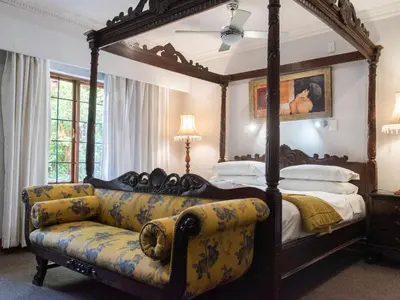 a bedroom with a large canopy bed with a couch at Aanmani Rose Guesthouse in Pretoria