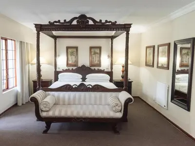 a large bed with a large wooden frame in a room at Aanmani Rose Guesthouse in Pretoria