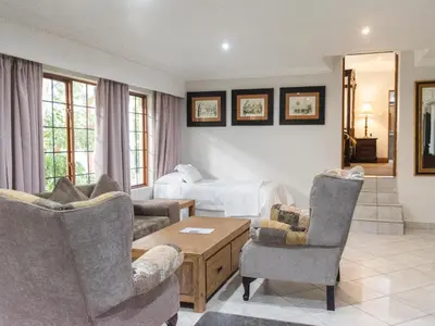 a living room with two chairs and a bed at Aanmani Rose Guesthouse in Pretoria