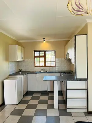 a kitchen with white cabinets and a table in it at Ka Tembe Self Catering Lodge in Polokwane