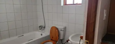 a bathroom with a toilet and a bath tub with a wooden seat at Ka Tembe Self Catering Lodge in Polokwane
