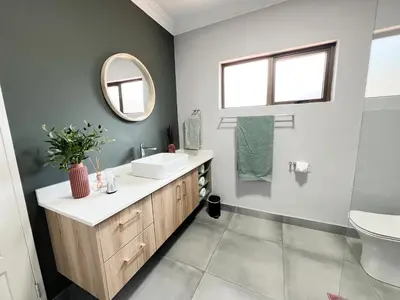 a bathroom with a sink and a mirror at Afrique134 Olive Tree Private Courtyard Suite in Pretoria
